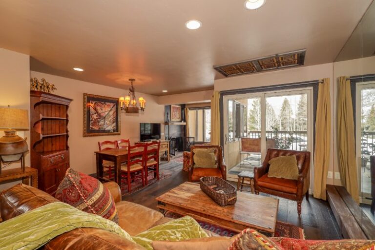 Living room with leather sofas and a balcony door at 108 Fallridge near the Vail Golf Course